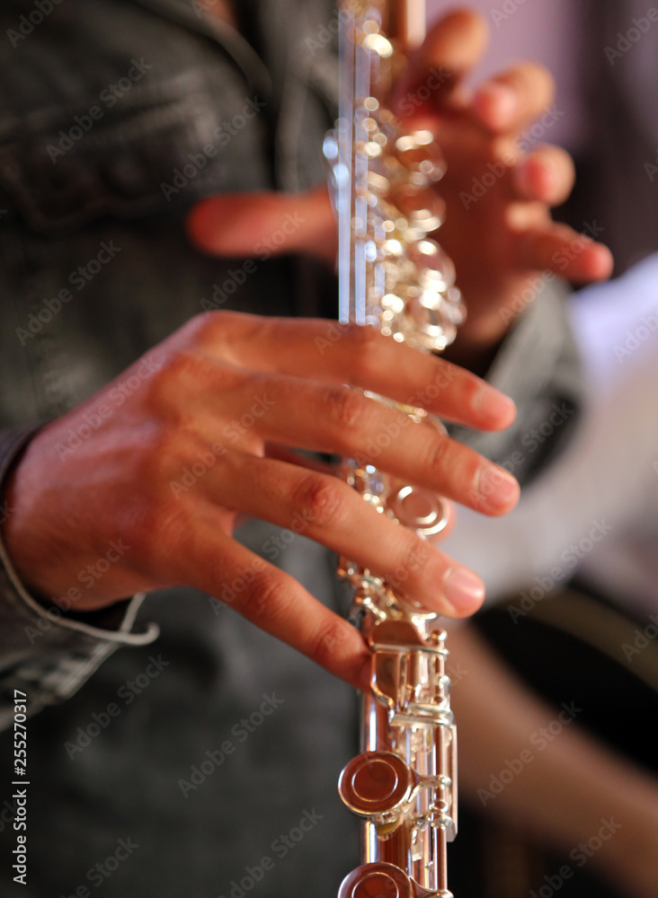 Obraz premium Professional elegant man flutist performing in a white room, hands close up