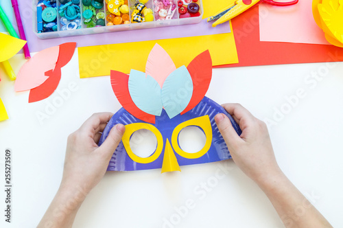 A child makes a bird mask out of paper. Master class crafts. Tropical Parrot.