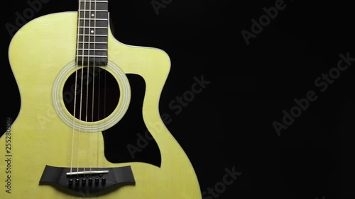 Acoustic guitar showing body shape on the black background with dolly shot. 