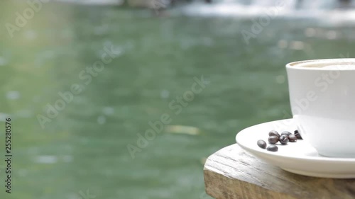 Pan motion effect of a cup of coffee near by the water fall. 