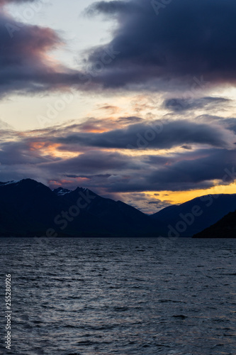 peaceful landscape during sunset with dramatic sky above the lake and mountain range