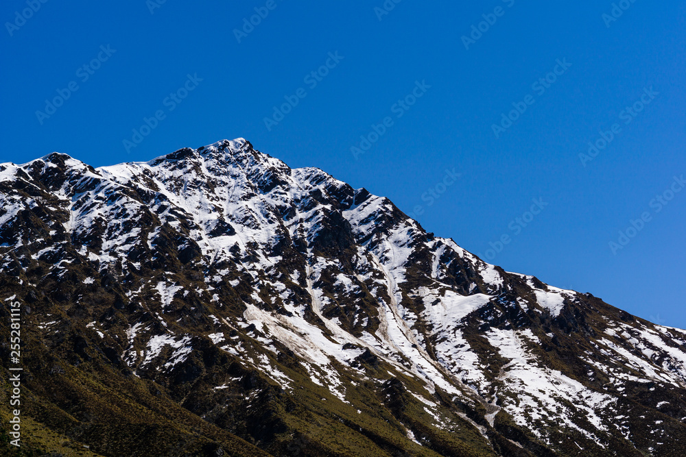 mountain peak covered by snow, sunny day with cloudless blue sky