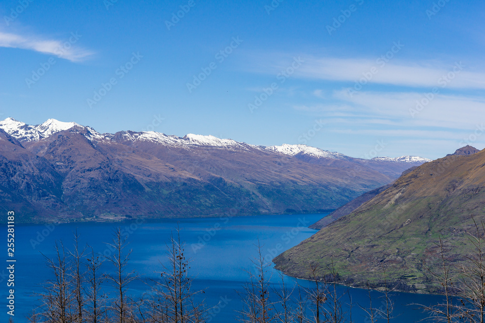 peaceful landscape during sunny day with calm sky above the lake and mountain range, perfect hiking area