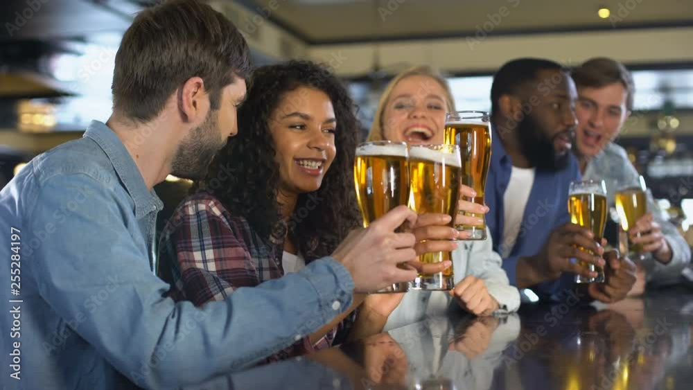 Emotional sport fans clinking beer glasses, celebrating team victory in pub Emotional sport fans clinking beer glasses, celebrating team victory in pub