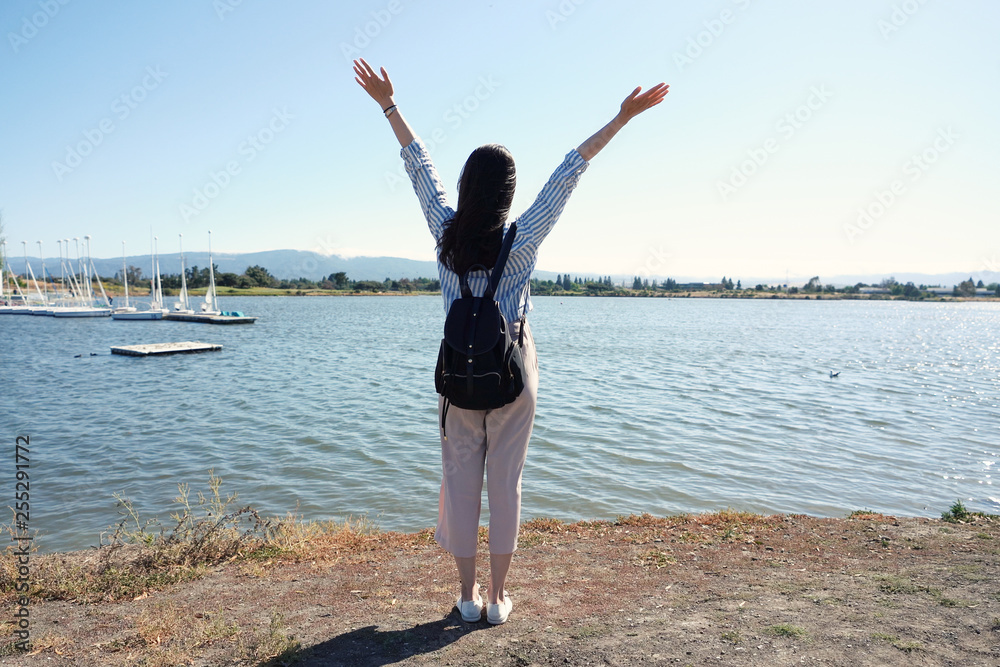Happy freedom woman with open arms looking at blue sea horizon outdoors. Carefree person living a free life. full length back view of asian travel lady love nature lake river water wild near the port Happy freedom woman with open arms looking at blue sea horizon outdoors. Carefree person living a free life. full length back view of asian travel lady love nature lake river water wild near the port
