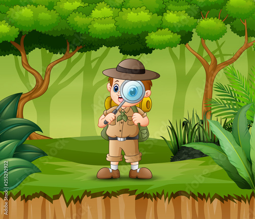 Boy explorer with magnifying glass in the forest