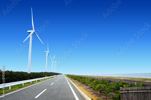 海岸沿いにある風力発電のための風車とまっすぐな道