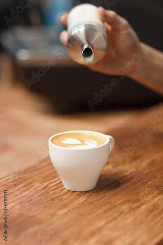 Barista pours sugar into the prepared cappuccino