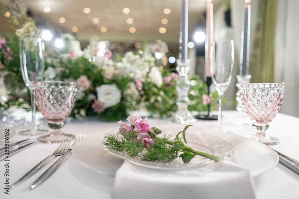 Closeup Table setting with plates and tableware, adorned with flowers. Floral decoration for wedding ceremony romance dining. Wedding banquet , festive decor. Concept of service and catering.