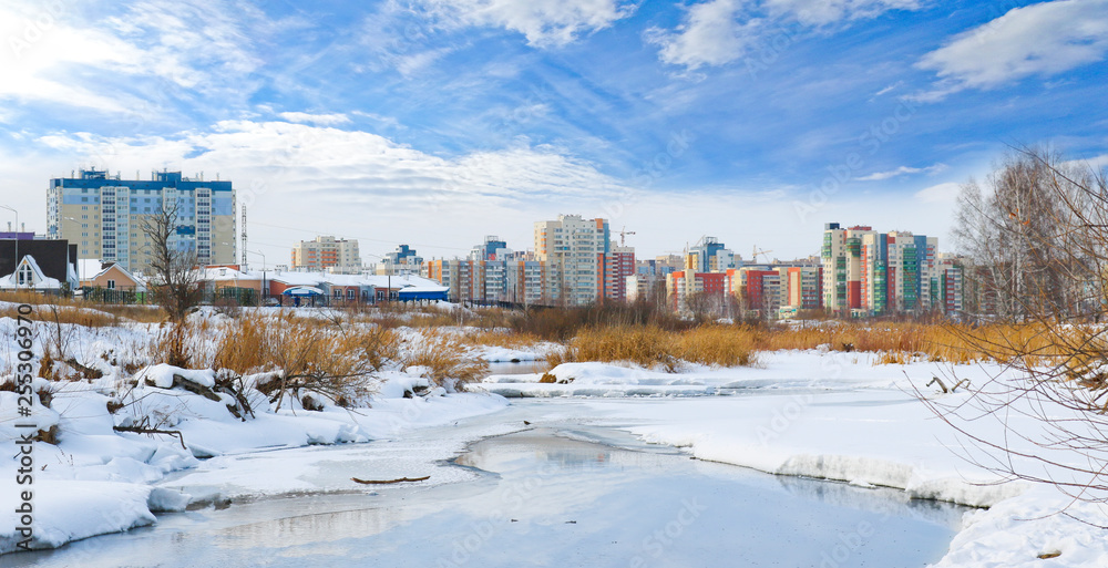 Panorama of the city with colorful new buildings on the river bank in winter.