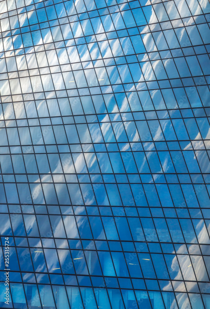 Sky and white clouds are reflected in glass wall of modern skyscraper Sky and white clouds are reflected in glass wall of modern skyscraper