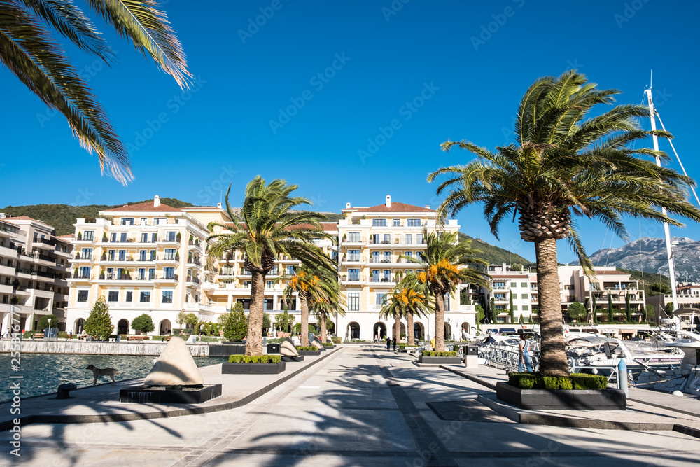 TIVAT, MONTENEGRO - SEPTEMBER 29, 2018: Tourists walking on sunny seafront of Tivat city.