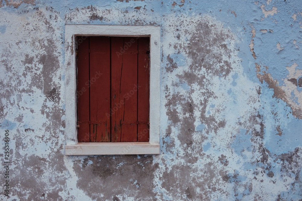 Old wooden window on weathered blue wall. Old architecture