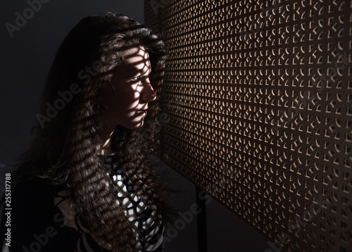 Beautiful girl, with a sporty figure, with the shadow of the screen on his face, thoughtfully peering out the window