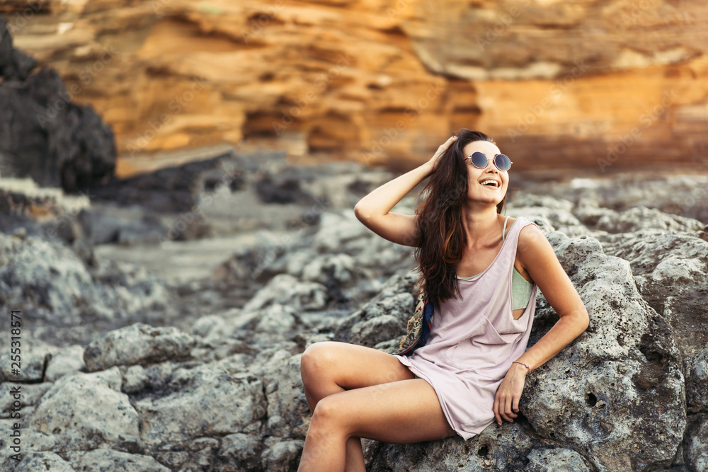 Pretty long hair brunette tourist girl relaxing on the stones near sea. Pretty long hair brunette tourist girl relaxing on the stones near sea.