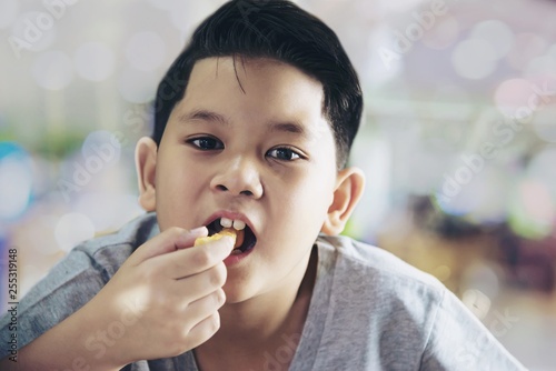 Boy eating French fries potato with dipped sauce over white wooden table