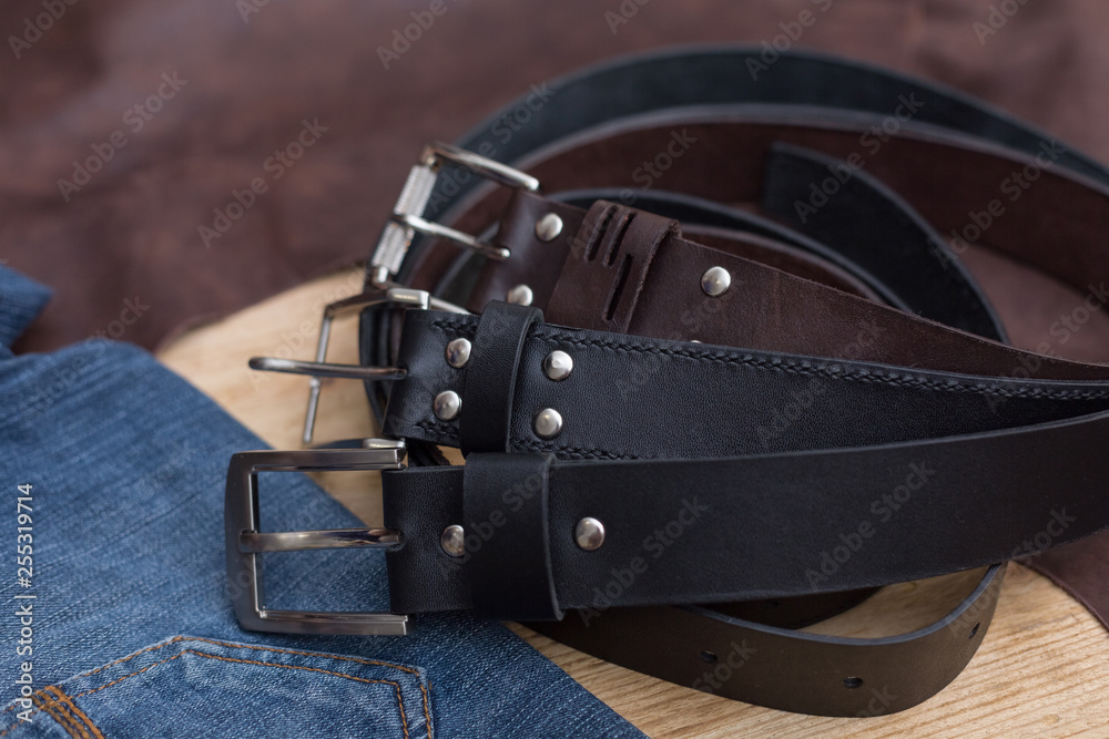 Three leather belt with jeans textile on wood Three leather belt with jeans textile on wood