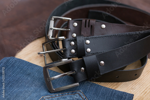 Three leather belt with jeans textile on wood