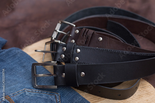 Three leather belt with jeans textile on wood