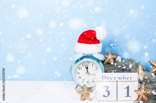Calendar, blue alarm clock, branches fir tree and golden stars on blue textured background