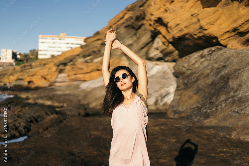Naklejka premium Pretty long hair brunette tourist girl relaxing on the stones near sea.