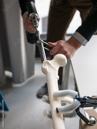 Young doctors and medical students train with instruments and plastic bones for orthopedic surgeries training.