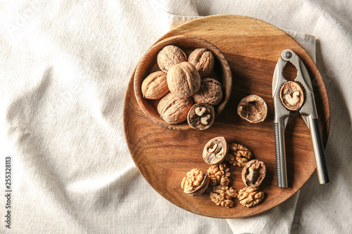 Tasty walnuts with nutcracker on plate