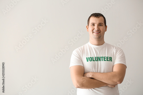 Young male volunteer on light background