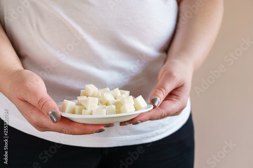processed products, unhealthy diet. overweight woman with amount of sugar cubes on plate. simple carbohydrates, sugar addiction, diabetes prevention.