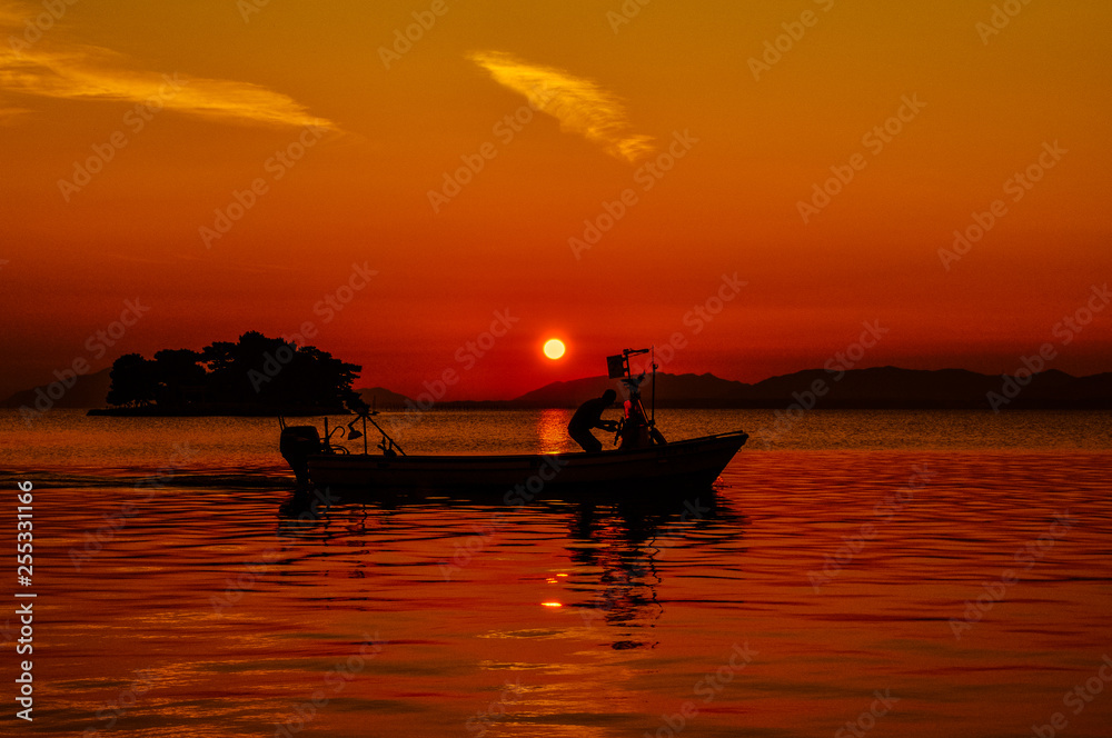 Man driving a boat with the setting sun in the background