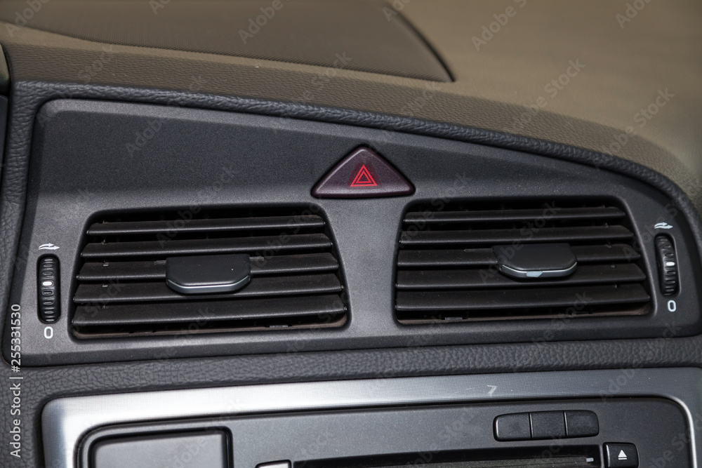 Close-up on emergency button in red color near the duct in the interior of an modern car in gray after dry cleaning