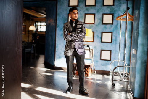 Young indian handsome business man at evening suit on restaurant against wall with frames.