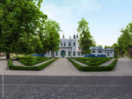 Slovakia, Kosice - May 2, 2018: Entrance to the City Park (Mestsky park) Kosice. Neatly trimmed lawns, trees and a white building in the distance in Kosice City Park in a spring sunny morning