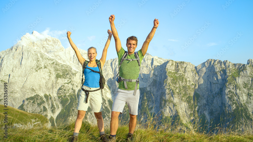 PORTRAIT: Smiling hiker couple outstretch their arms in celebration of fun hike