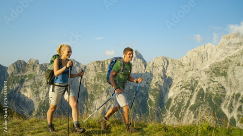 Sporty tourist couple trekking in the stunning Alps on a sunny summer day.