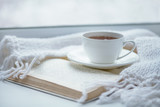 Tea drinking. The woman in a knitted, white pullover holds a cup of hot tea in her hands. Cozy weekends, winter drinks.