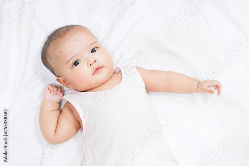 Asian newborn baby girl lying down on white bed