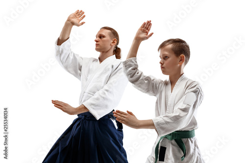 Man and woman fighting at Aikido training in martial arts school. Healthy lifestyle and sports concept. Man with beard in white kimono on white background. Karate woman with a concentrated face.