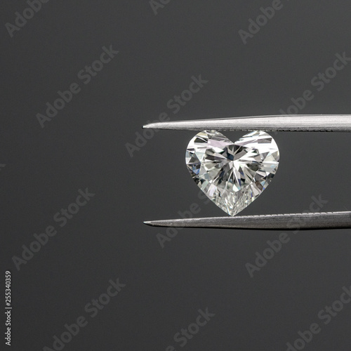 Heart shape diamond with tweezers on black background