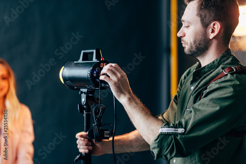 young beaded man setting the flash before photo session . close up photo. hobby, lifestyle