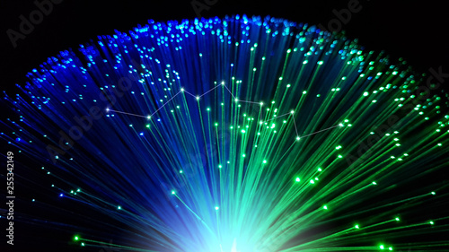 Blue and green optical fiber cables with shining tips on a black background