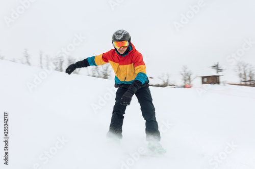young stylish snowboarder trying to take a balance, full length photo.athlete skiing down