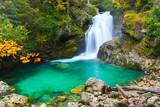 Autumn forest colors with small turquoise waterfall and lake in natural park of Vintgar river gorge Slovenia
