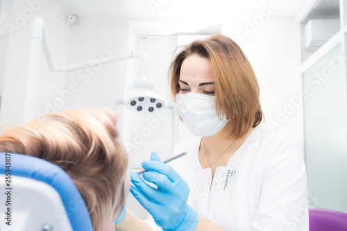 Young beautiful woman dentist treats teeth to woman patient