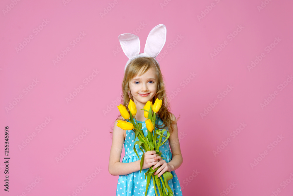 Cute little girl in the form of an Easter Bunny with a bouquet of yellow tulips. concept of holidays, fashion and beauty. Happy Easter! Selective focus.