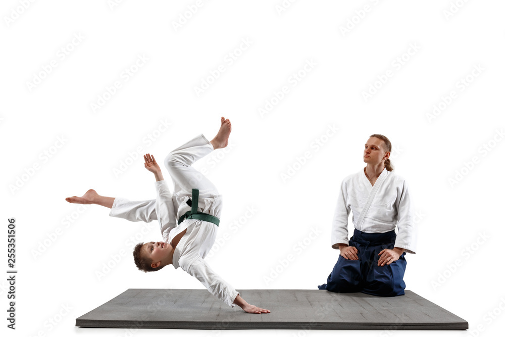 Man and teen boy fighting at Aikido training in martial arts school. Healthy lifestyle and sports concept. Fightrers in white kimono on white background. Karate men with concentrated faces in uniform. Man and teen boy fighting at Aikido training in martial arts school. Healthy lifestyle and sports concept. Fightrers in white kimono on white background. Karate men with concentrated faces in uniform.
