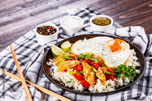 Grilled chicken meat with rice and fried egg on wooden table