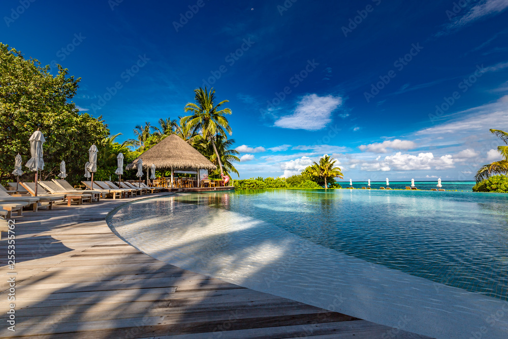 Beautiful poolside and sunset sky. Luxurious tropical beach landscape, deck chairs and loungers and water reflection