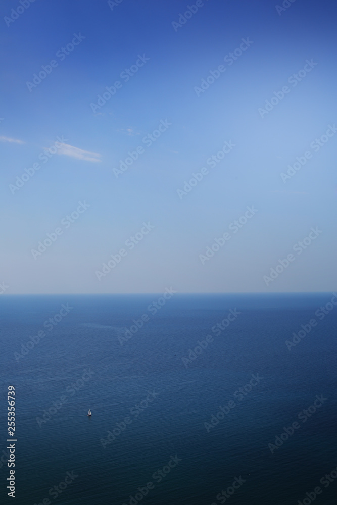 White sail on a background of blue sea from a height