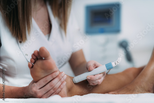 Laser therapy. Physical therapist treating patient's ankle joint photo